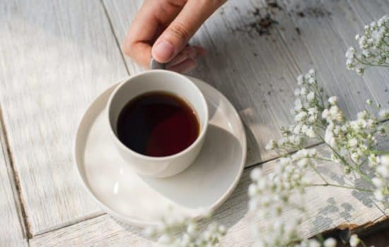 Hand on a white tea cup with CBD Tea