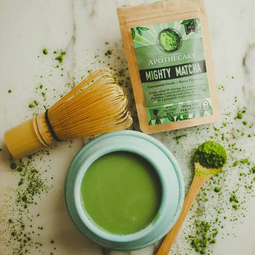 CBD Matcha Flat Lay with 3 servings of Matcha, Whisk and Spoon next to a cup of Matcha